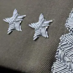 Trzy gwiazdki w wojsku, symbol wysokiej rangi, zdobią mundur obok ozdobnego naramiennika.