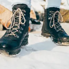 Czarne, sznurowane buty zimowe na śniegu. Dowiedz się, jak impregnować buty domowym sposobem, by chronić je przed wilgocią.