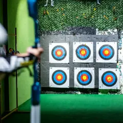 Strzelnica łucznicza, gdzie można strzelać z łuku. Tarcze wiszą na ścianie, a łucznik celuje.