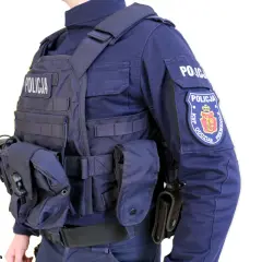 Policjant w pełnym rynsztunku, z kamizelką kuloodporną z napisem "POLICJA" i naszywką "KSP ODDZIAŁ PREWENCJI".