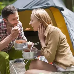 Para karmi się pysznym jedzeniem pod namiotem, ciesząc się wspólnym posiłkiem na łonie natury.
