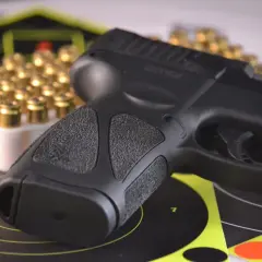 Pistolet i naboje na tarczy strzelniczej. Dokument potwierdzający, że osoba jest dopuszczona do posiadania broni.