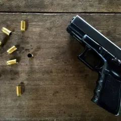 Czarny pistolet i łuski na drewnianym stole. Jaka broń na pozwolenie kolekcjonerskie?