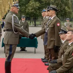 Podporucznik skrót. Uroczystość wręczenia odznaczeń wojskowych. Dwóch oficerów w mundurach ściska sobie dłonie.