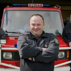 Trzech strażaków OSP pozuje przed wozem strażackim.