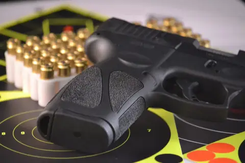 Pistolet i amunicja na tarczach strzeleckich, symbolizujące pozwolenie na broń do ochrony osobistej.