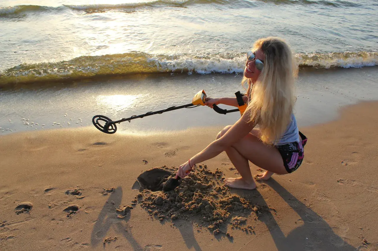 Dziewczyna z wykrywaczem metali na plaży. Czy można chodzić z wykrywaczem po plaży? Ona właśnie kopie w piasku, szukając skarbów.