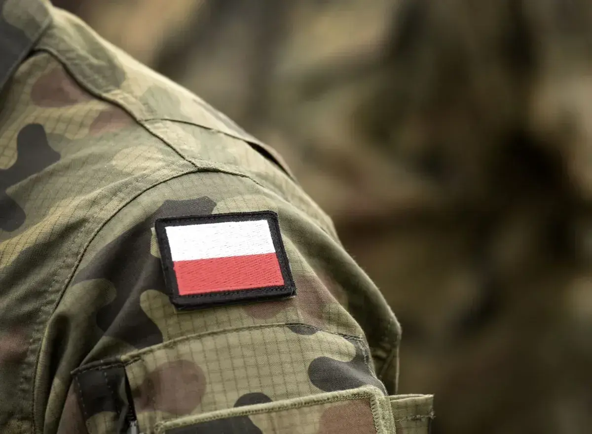 Na mundurze widoczna naszywka z flagą Polski. To symbol dumy i tradycji, nawiązujący do historii, w tym do stopni wojskowych II RP.