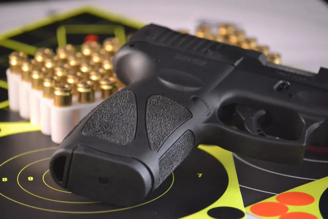 Pistolet i amunicja na tarczach strzeleckich, symbolizujące pozwolenie na broń do ochrony osobistej.