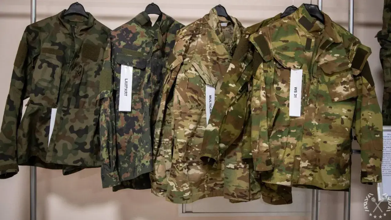 Rzędy kurtek w różnych kamuflażach wojskowych, od klasycznych leśnych po wielobarwne Multicam. Każda z nich gotowa na misję.